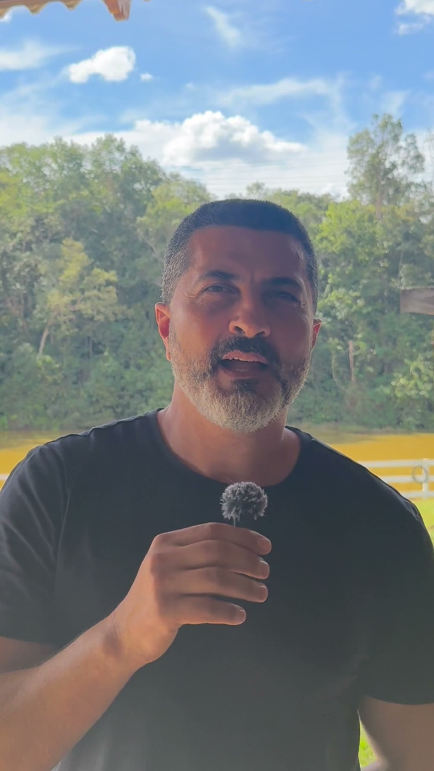 Márcio, cliente do Laguna Magnólia, à beira do rio segurando uma flor do campo